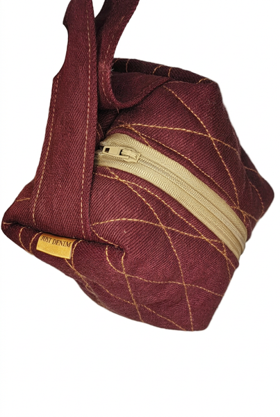 Angled view of burgundy Boxed Mini Make-up bag showing its boxed shape, loop handle, cream zip and gold contrast stitching. 