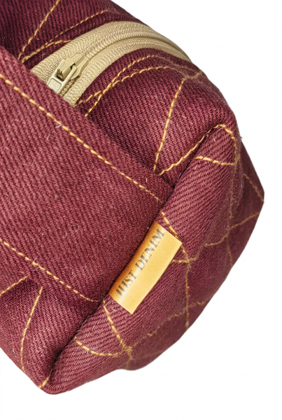 Close-up of Boxed Mini-me Makeup Bag showing burgundy fabric, gold stitching, cream zip and Just Denim label. 